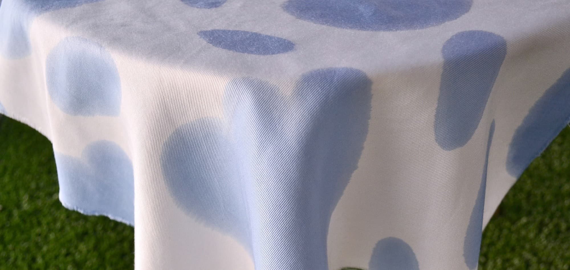 Blue dot printed textile draped outdoors over grass