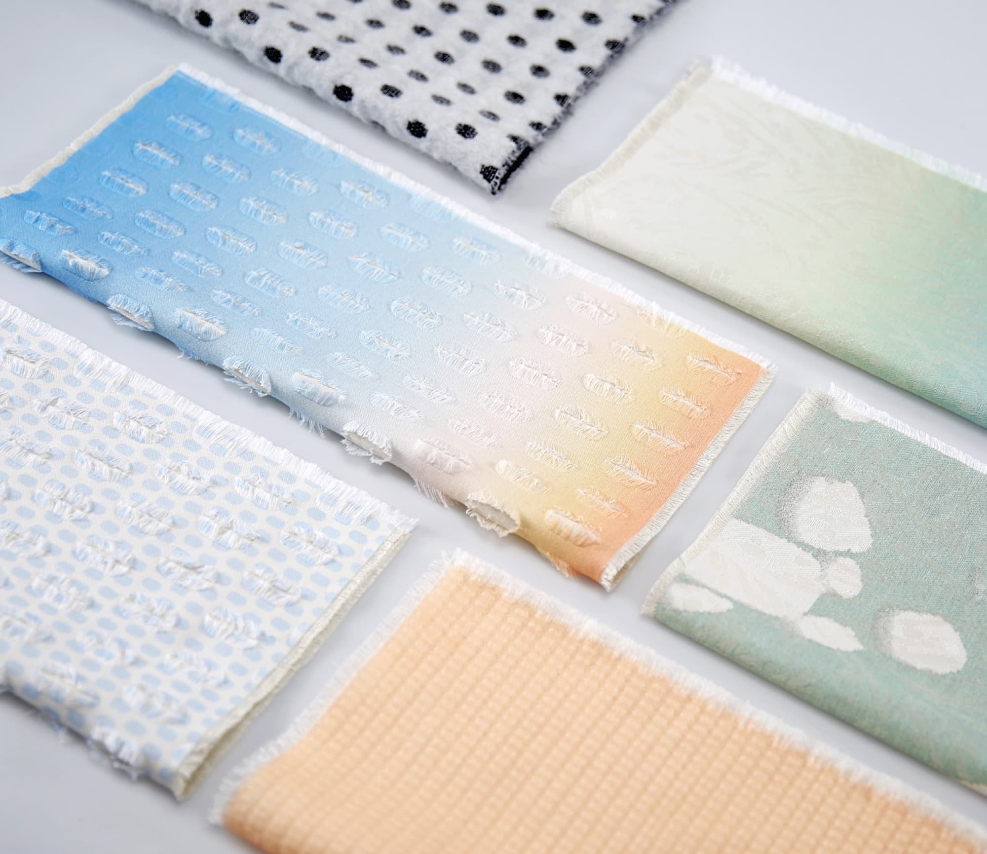 Flatlay of six organic cotton textile swatches in a gradient of natural tones