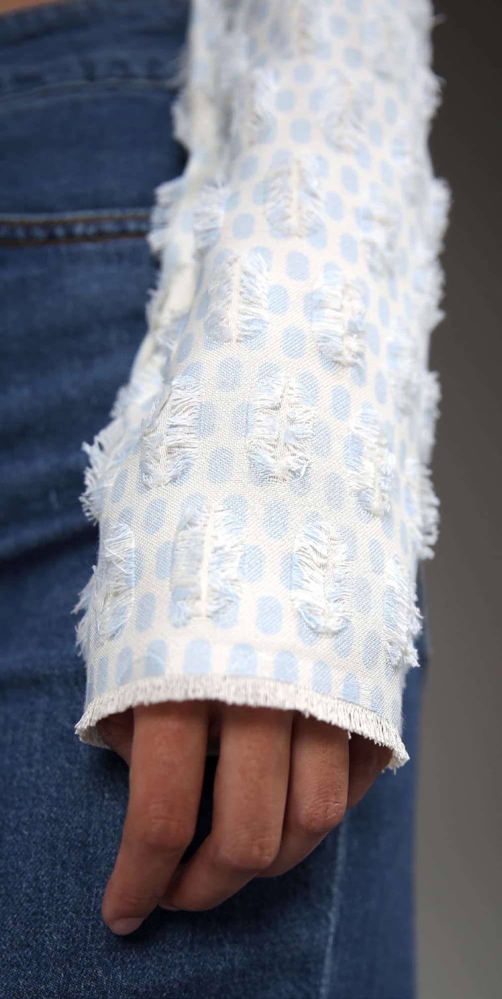 Close-up of frayed-edge jacquard cuff in pale blue
