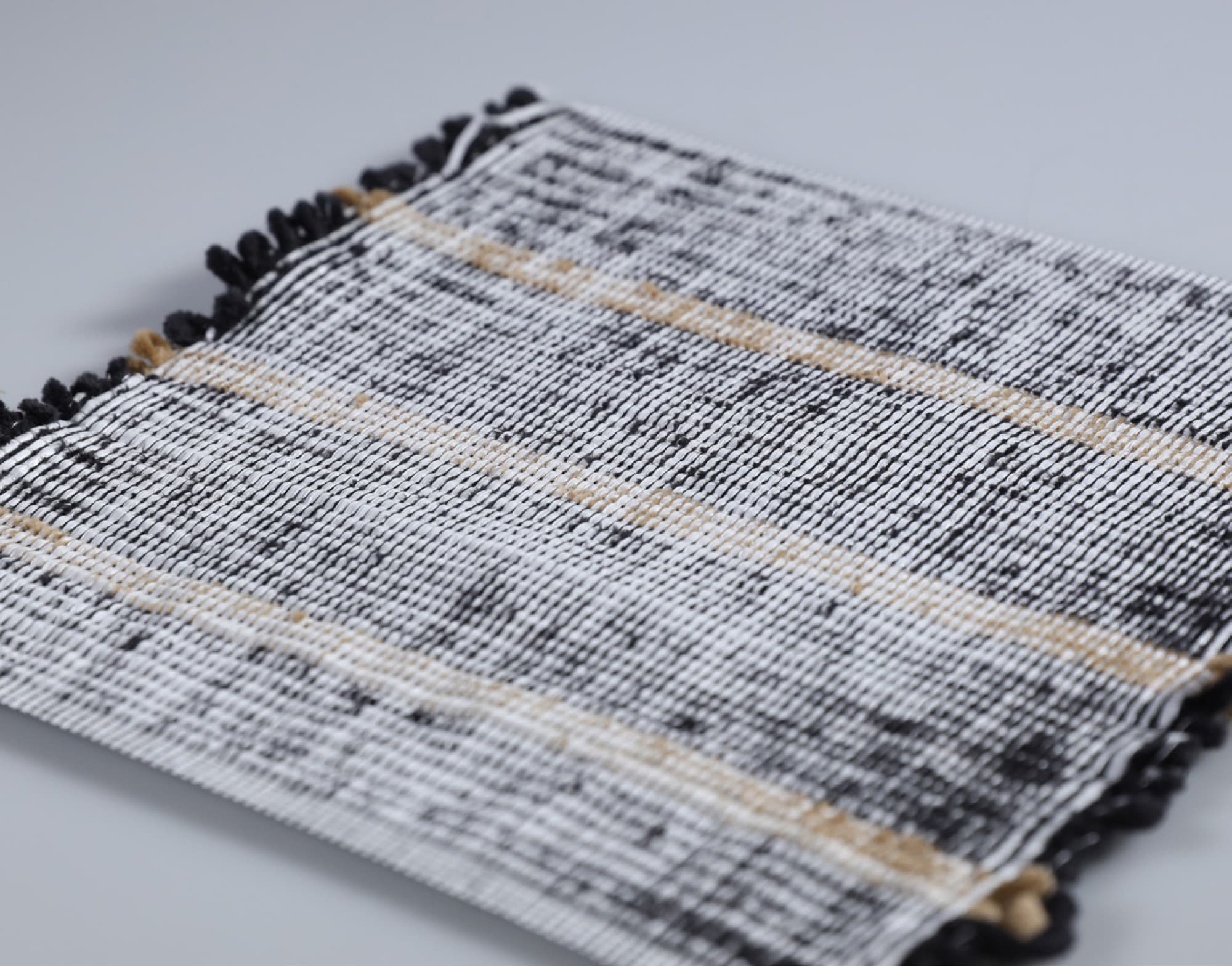 Handwoven textile with looped white and black fringe